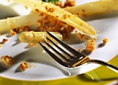 Weisser Spargel mit Walnussbröseln auf Teller mit Gabel