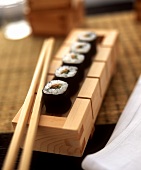 Hoso maki with fish and vegetables in wooden box with chopstick