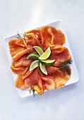 Smoked salmon slices with dill and lime wedges