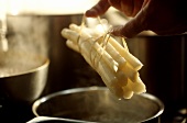 Lifting freshly boiled white asparagus out of the pan