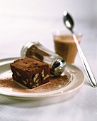 Brownie, sprinkled with cocoa, on a plate; coffee