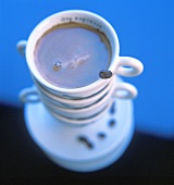 Kaffee in Tasse mit Kaffeebohne auf Kaffeetassenstapel