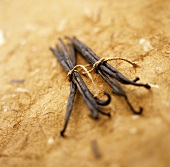 Two bundles of vanilla pods on a brown background