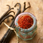 Saffron threads in a jar, vanilla pods beside it