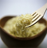 Sauerkraut on a fork above a brown bowl