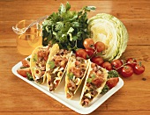 Tacos with meat, tomatoes and olives; salad; tomatoes; oil