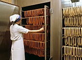 Sausage making: taking sausages out of smoking chamber