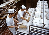 Bäcker bereiten Brote zum Einschieben in den Backofen vor