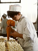 Female pastry chef decorating gateaux with piping bag