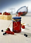 Berry jelly in a jam jar surrounded by fresh berries