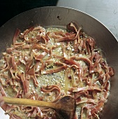 Frying strips of bacon in butter