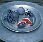 Fresh figs and black grapes on pewter plate