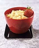 Rice pudding with strawberry in a red bowl