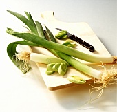 Leek, partially sliced, on wooden chopping board