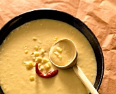 Sweetcorn soup with chili pepper and wooden spoon