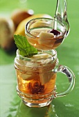 Cider punch in glass & ladle in front of apples & pears