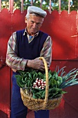 Gärtner hält Korb mit frischem Gemüse