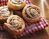 Raisin snails with icing sugar on checked cloth