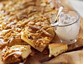 Apple cake with flaked almonds; cream in glass