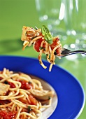 Spaghetti with tomatoes and artichokes on fork and plate
