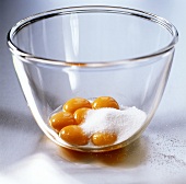 Egg yolk with sugar in glass bowl