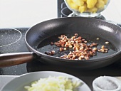 Frying diced bacon in frying pan