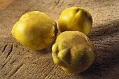 Three quinces on wooden background