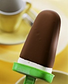 Chocolate-coated vanilla ice cream with green plastic stick