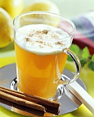Tea punch with cream topping and cinnamon in glass cup