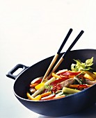 Vegetables with strips of turkey in wok; chopsticks
