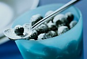 Sugared blueberries in blue bowl and on spoon
