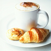 Cup of milky coffee and Danish pastry