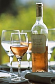 Rosewein in Gläsern und Flasche auf Tisch im Freien