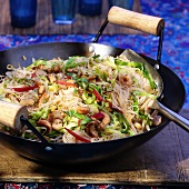 Thai noodles with meat, vegetables and peanuts in wok