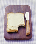 Buttered bread on bread board, a bite taken