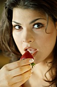 Junge lateinamerikanische Frau mit frischer Erdbeere