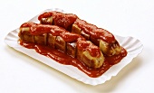 Fried sausage with ketchup on paper plate