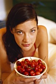 Young woman holding bowl of fresh cherries