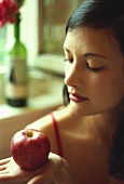 Young woman looking at red apple on her hand