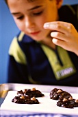 Kleiner Junge bereitet Schokoladenplätzchen zu