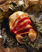 Quail wrapped in bacon on vine leaves