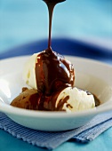 Pouring chocolate sauce over vanilla and chocolate ice cream