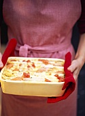 Hands holding asparagus lasagne with salmon and tomatoes