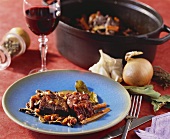 Braised beef with bacon and carrots; glass of red wine