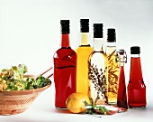 Various bottles of vinegar, with a bowl of salad