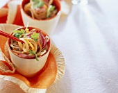 Soya noodles on chopsticks with vegetables and parsley