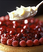 A raspberry and cherry tart with cream on spoon