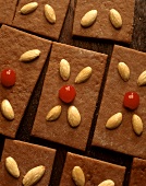 Square dark gingerbreads with almonds and cherries on top