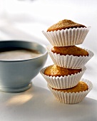 Vier Mini-Muffins aufeinander gelegt, daneben Milchkaffe