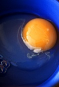 Aufgeschlagenes Ei in blauer Schüssel